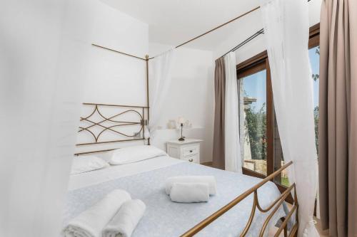 a white bedroom with a bed and a window at Villa Lu Nibaru 2 in Cannigione
