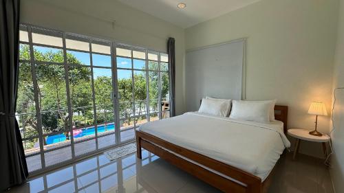 a bedroom with a bed and a large window at Greenery Hill in Ban Nok