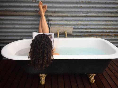 a woman laying in a bath tub with her legs in it at The Milkmans Shack in Dunorlan