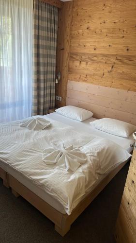 a bedroom with a large white bed with a wooden wall at Hotel Kukučka Apartament C102 Tatranská Lomnica in Vysoké Tatry