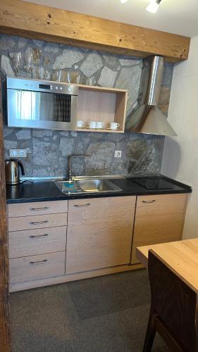 a kitchen with a sink and a stone wall at Hotel Kukučka Apartament C102 Tatranská Lomnica in Vysoké Tatry