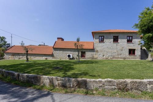 a large stone building with a grass yard in front of it at Casas do Bacelar by Liiiving in Quinchães