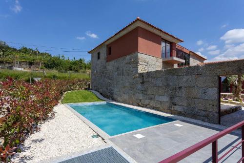 a swimming pool in front of a house at Casas do Bacelar by Liiiving in Quinchães