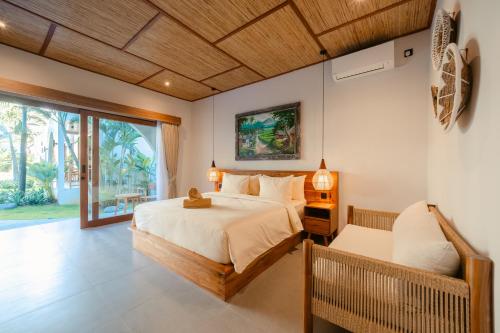 a bedroom with a bed and a chair and a window at Casa Nova Villa Uluwatu in Uluwatu