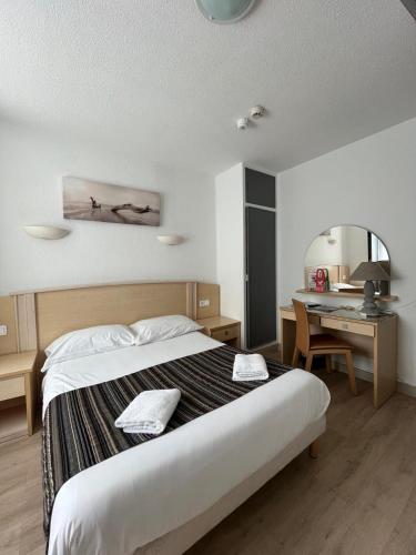a bedroom with a bed and a desk and a desk at Hotel De La Mer in La Tranche-sur-Mer