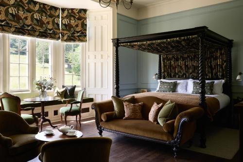 a bedroom with a bed and a couch and chairs at Dumbleton Hall in Broadway