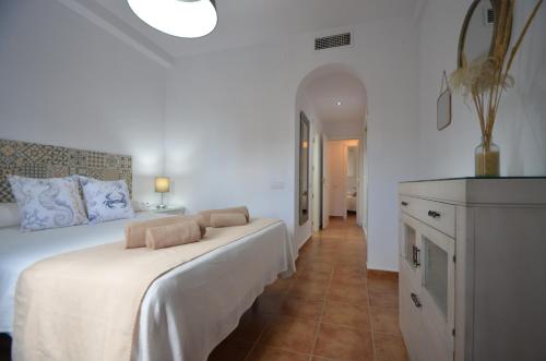 a white bedroom with a large bed and a hallway at La Marina Solmares in Isla del Moral
