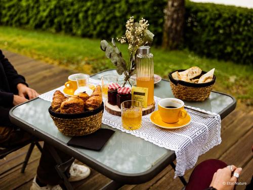 a table with baskets of bread and cups of coffee at Bulle forestière - Etat Nature in Magnières