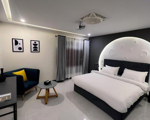 a bedroom with a large white bed and a chair at Hotel Desert Bloom Skardu in Skardu