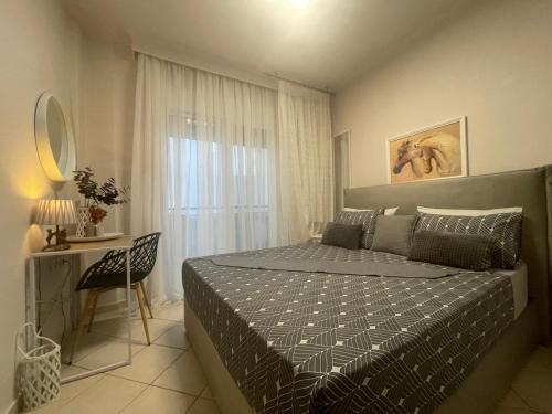 a bedroom with a bed and a table and a window at Olena Apartment in Nea Moudania
