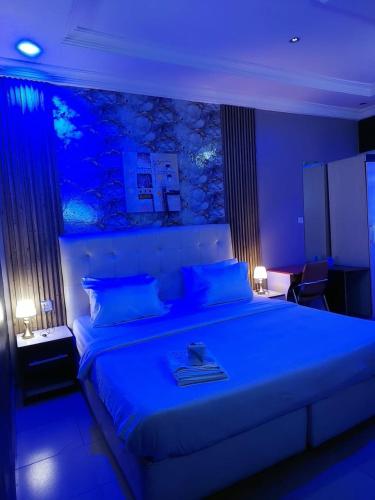 a bedroom with a large bed with blue lighting at Pulville Boulevard Hotel in Suru Lere