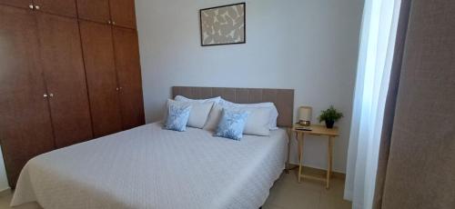 a bedroom with a white bed with blue pillows at Condo Sunset in Cabo San Lucas