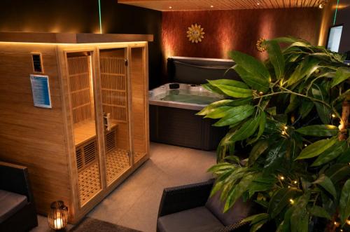 a bathroom with a sauna with a tub and a plant at Maison Samree met Indoor Wellness in La-Roche-en-Ardenne