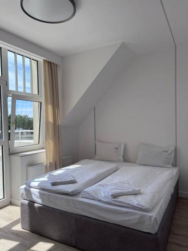 ein weißes Bett in einem Zimmer mit großem Fenster in der Unterkunft Villa Amadea in Misdroy