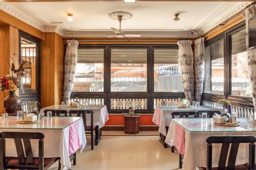 a restaurant with tables and chairs and windows at Hotel Swastik in Kathmandu