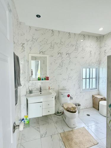 a white bathroom with a toilet and a sink at Paiyawadee House khaoyai in Ban Hua Phrong