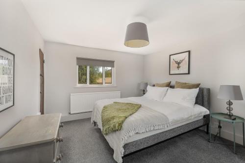 a white bedroom with a bed and a window at Malvern House in Banbury