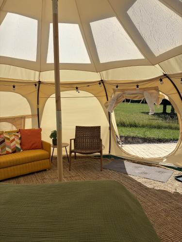 a tent with a couch and a chair in a room at Glamping, Tåsinge - Svendborg in Svendborg