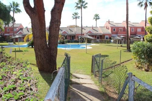 uma cerca com uma árvore ao lado de uma piscina em Apartamento Pink Mariposas em Chiclana de la Frontera