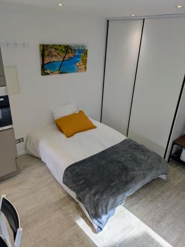 a bedroom with a bed with a orange pillow on it at Charmant Cocon, terrasse proche Clermont in Tallende