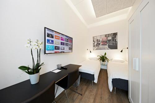 a room with two beds and a desk with a computer at Living Suites in Nærum