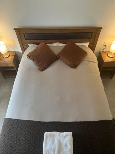 a bed with two pillows on it with two tables at Ingloo in Puerto Natales