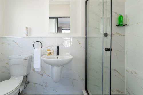 a white bathroom with a toilet and a sink at #AlimamaSpaces The Contemporary Retreat in Midrand