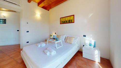 a bedroom with a white bed with a table on it at Borgo del Torchio C8 ByBookinggardalake in Manerba del Garda