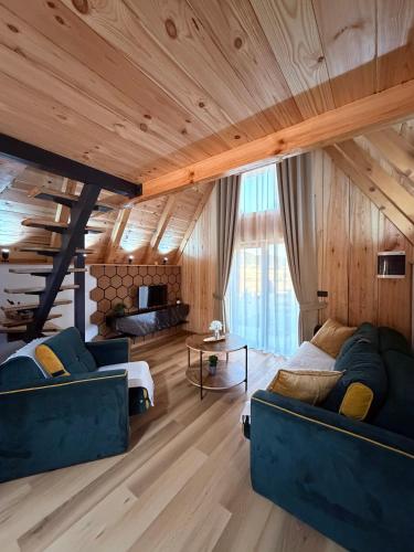 a living room with two blue couches and wooden ceilings at Alvearium Chalets in Žabljak