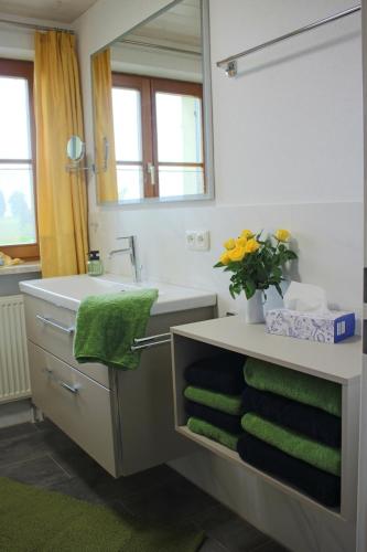 a bathroom with a sink and a mirror and green towels at Ferienwohnung Freißl in Rottenbuch
