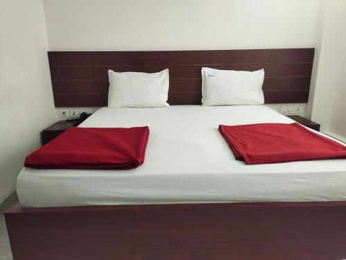 a large bed with two red pillows on it at Raya Raj Anugraha in Kumbakonam