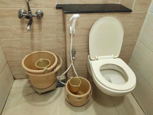 a bathroom with a toilet and two buckets at Raya Raj Anugraha in Kumbakonam