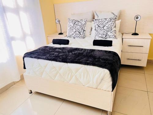a white bed in a bedroom with two lamps at MrP Guest House in Kokstad
