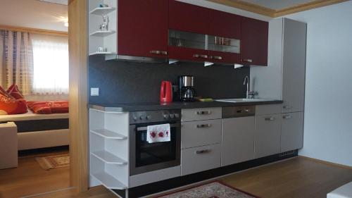 a kitchen with red cabinets and a stove top oven at Ferienwohnungen Fahringer Diana in Kössen
