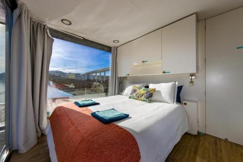 a bedroom with a large bed with a large window at SLEEPBOAT Floating House Boat Oporto Douro in Porto