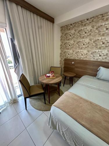 a hotel room with a bed and a table and a desk at Flat em hotel Promenade Itaguaí in Itaguaí