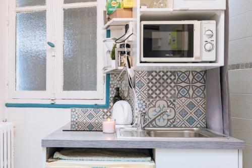 a small kitchen with a microwave and a sink at Chic Studio Apartment for 3 - La Villette! in Paris