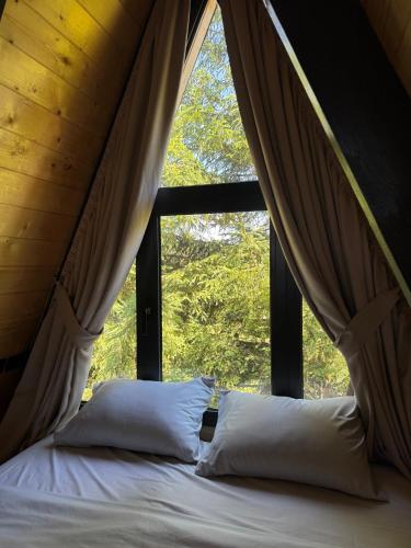 a bed in a room with a large window at Forest Whisper Lux - A-frame cabin with private hot tub in Kovačka Dolina