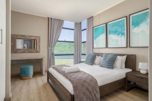 a bedroom with a large bed with a large window at Azure Guesthouse in Ballito