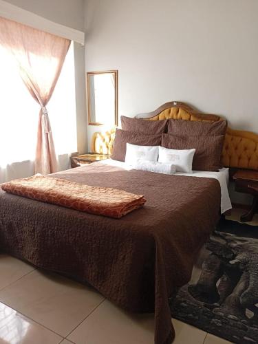 a bedroom with a large bed with brown sheets and a window at Uptown Inn GuestHouse in Parys