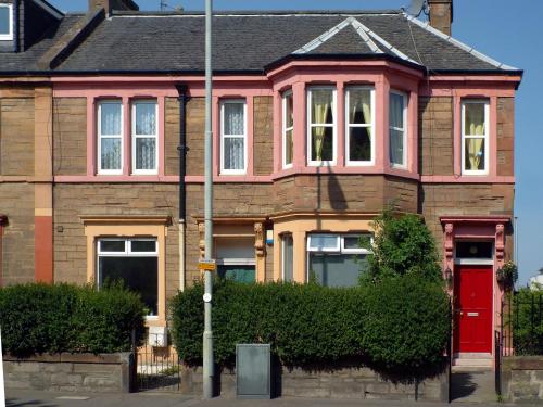 una casa rosa con una puerta roja en una calle en Badjao B&B, en Edimburgo