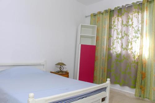 a bedroom with a white bed and a curtain at Résidence Chahed in Hammam Sousse