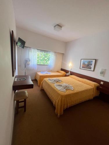a bedroom with two beds and a desk and a window at Hostería Santa Bárbara in Villa Gesell