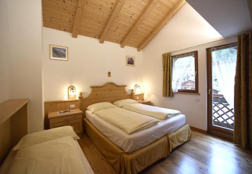 a bedroom with two beds and a window at Romantic Chalet Dolomiti in Val di Zoldo