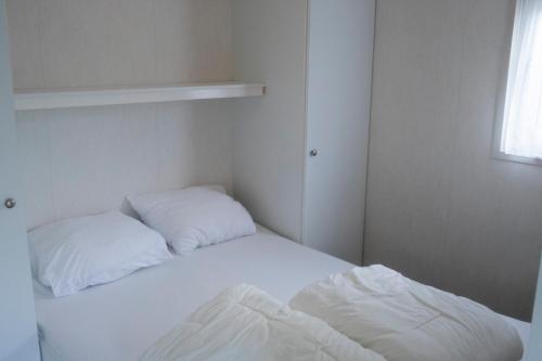 a bedroom with two beds with white sheets and a window at Chalet nr 43 in Molkwerum