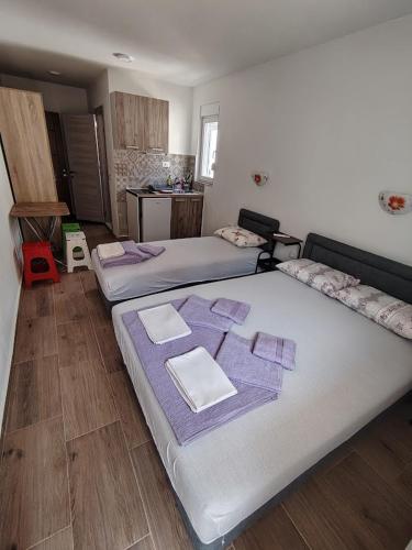 a room with three beds with purple towels on them at Apartmani CECA 012 Sutomore in Sutomore