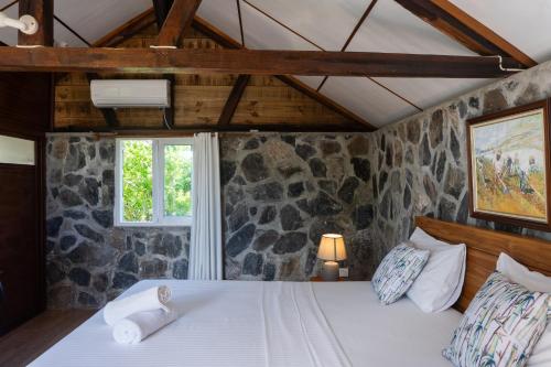 a bedroom with a white bed with a stone wall at Residence Foulsafat in Rodrigues Island