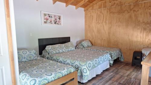 a small room with two beds and a table at Alojamiento Parcela El Aromo in Paine