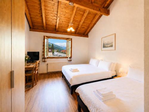 ein Schlafzimmer mit zwei Betten, einem Schreibtisch und einem Fenster in der Unterkunft Alpine Hotel Reich in Cazis