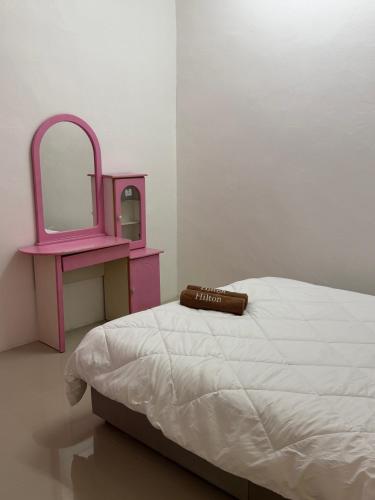 a bedroom with a bed with a pink vanity and a mirror at Homestay Jerantut in Jerantut
